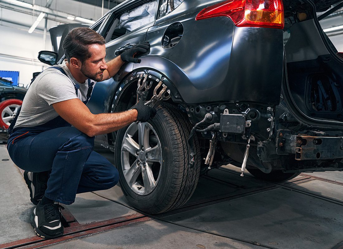 Insurance by Industry - A Young Mechanic Placing Two Double Clamps Above Car Tire During Repair